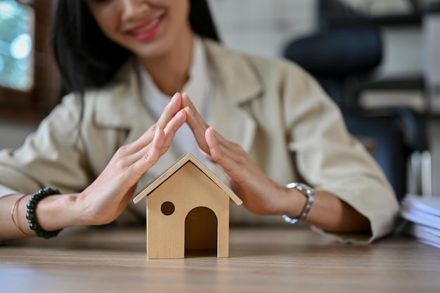 Female real estate agent or house insurance broker sits at her desk with a house model