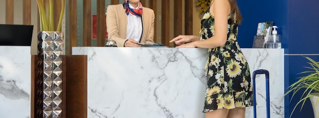 Female receptionist giving hotel information to woman traveller at check in counter