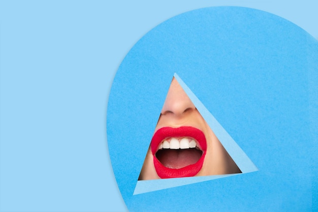 Female red lips peeking throught triangle in blue background