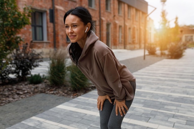 Female runner catching her breath during city jogging