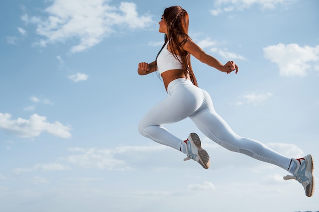 Female runner in white sportive clothes doing fitness