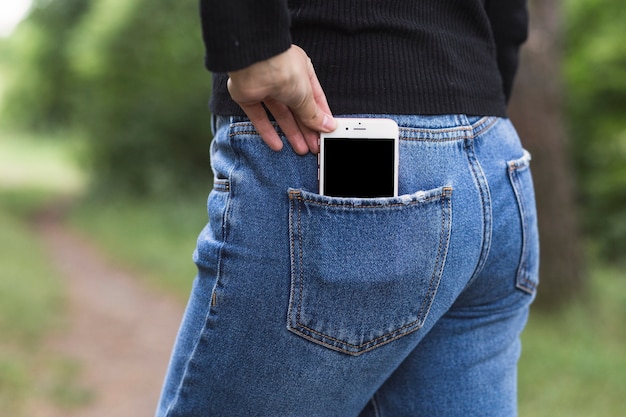 Female's hand taking cellphone from the jeans pocket