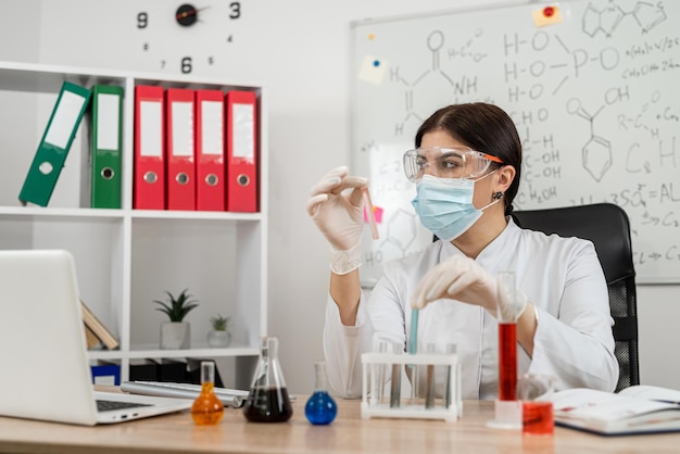 Female scientific laboratory looking on test tube with reagent for experiment