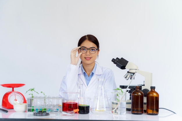 Female scientist holding her glasses and looking with both test tubes and writes experimental summary on clipboard while