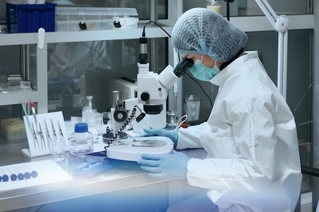 Female scientist looking through a microscope in laboratory.