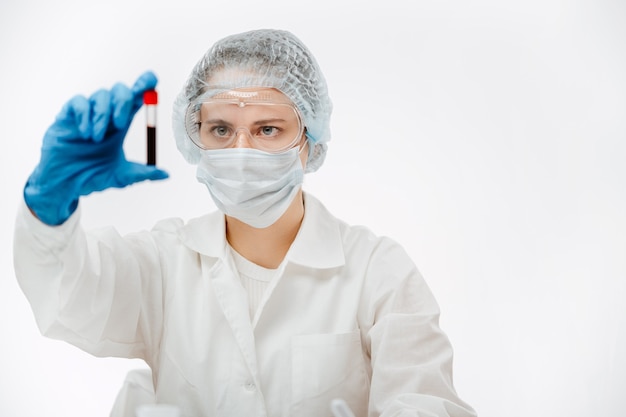 Female scientist in uniform holding tube of blood on white background