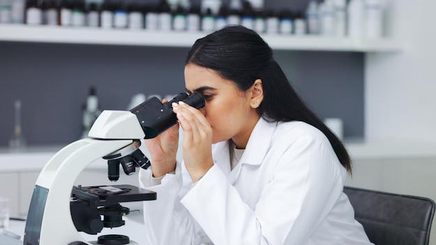 Female scientist using a microscope in a research lab Young biologist or biotechnology researcher working and analyzing microscopic samples with the latest laboratory tech equipment