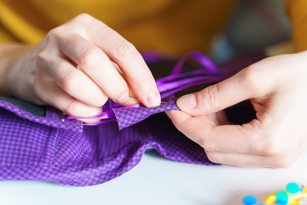 Female seamstress sewing corset with needle while working at her workplace