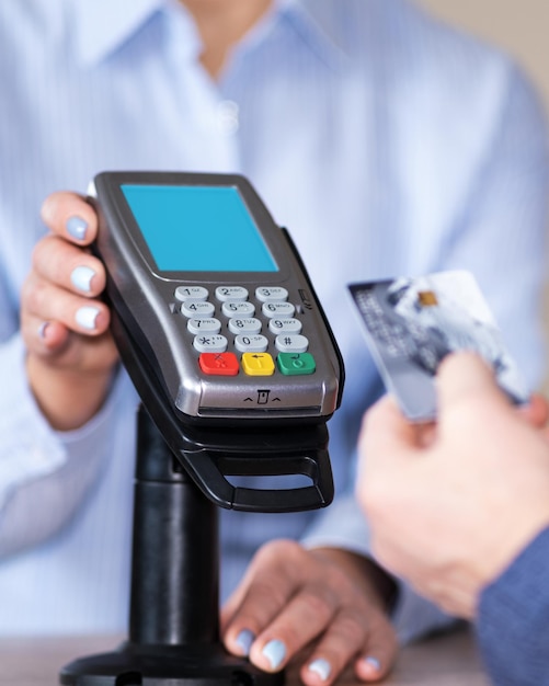 A female seller helps a buyer with online payment by credit card The man is ready to use a credit card to pay Cashless technology and credit card payment concept