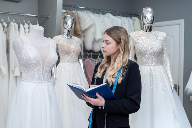 Female seller hold pen and notes near wedding dress in boutique