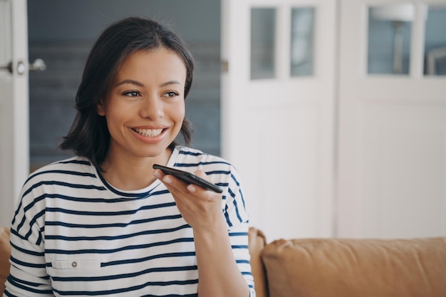 Female sends voice message by smartphone uses speaker phone enjoying online communication at home