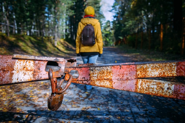 Female silhouette behind a rusty iron gate with a padlock. Woman enters a deserted closed park. Concept of violating prohibitions.