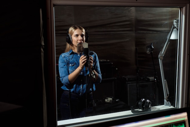 Female singing a sing with mobile phone at recording studio. You