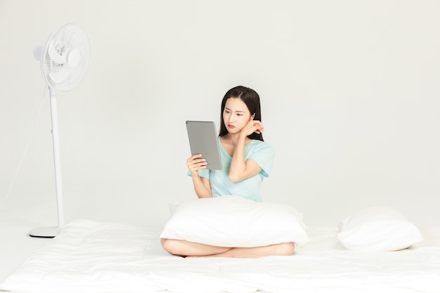 Female sitting on bed looking at tablet