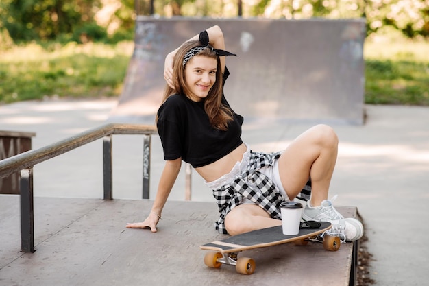 Female skater with a skateboard relaxing in the skating rink