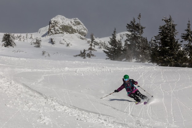 Female skier skiing downhill during sunny day in high mountains