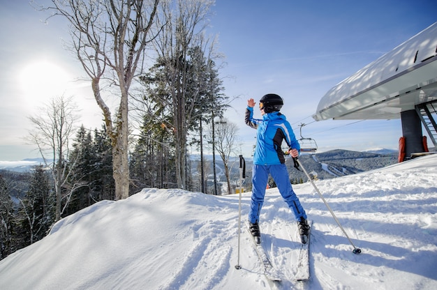 Female skier on the top of ski slope with ski-lift