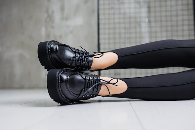 Female slender legs in black leggings and black leather loafers closeup Women's springsummer shoes 2023