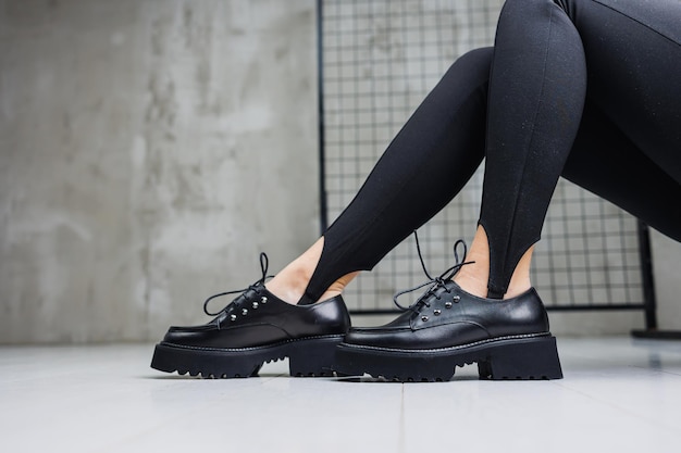 Female slender legs in black leggings and black leather loafers closeup Women's springsummer shoes 2023