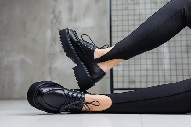 Female slender legs in black leggings and black leather loafers closeup Women's springsummer shoes 2023