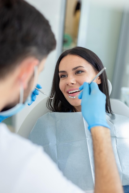 Female smiling client at dental procedure dentist using dental instruments in modern dental clinic