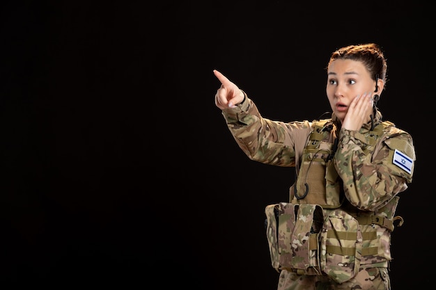 Female soldier in camouflage on black wall