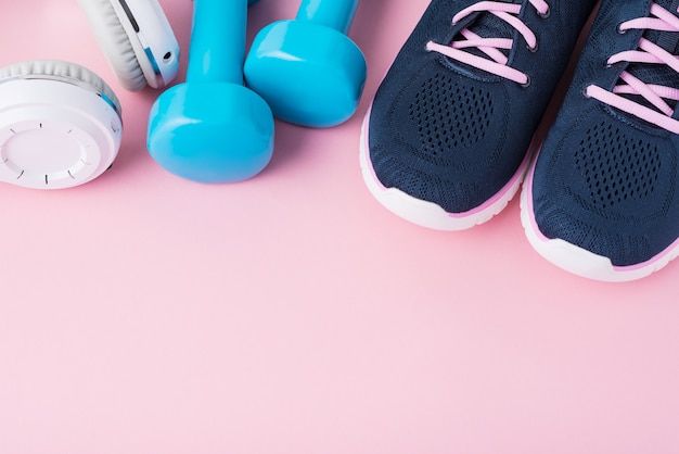 Female sport shoes, blue dumbbells andwhite headphones  with copy space, top view