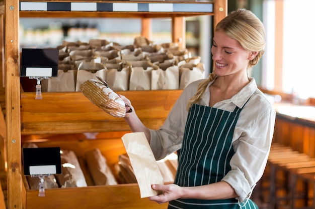 Female staff packing a bread in paper bag