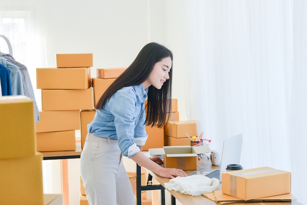 Female startup small business owner standing and working at notebook computer