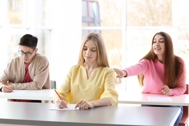 Female student asking answers from classmate at exam