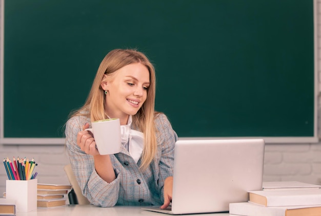 Female student drinking coffee or tea on lesson lecture in classroom at high school or college