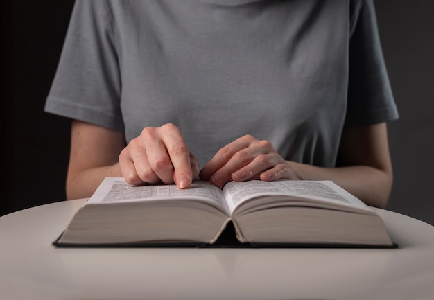 Female student hands close up, pointing on text in book or textbook, searching for information and reading at night.