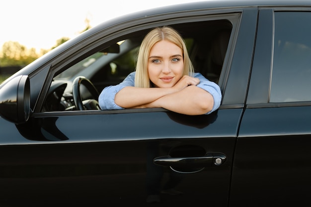 Female student poses in car, lesson in driving school. Man teaching lady to drive vehicle.