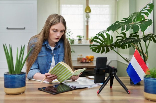 Female student sitting at home studying online looking at smartphone webcam