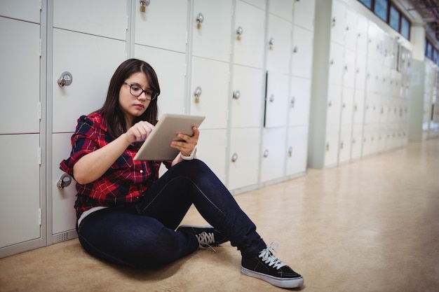 Female student using digital tablet in locker room