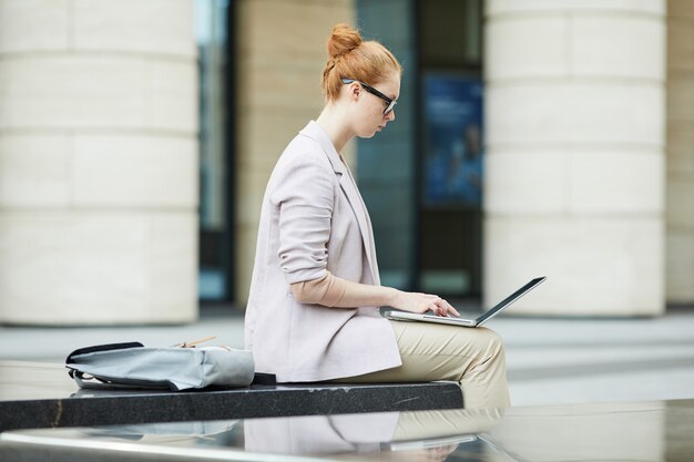 Photo female student using laptop outdoors