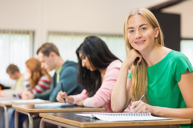 Female student with others writing notes in classroom