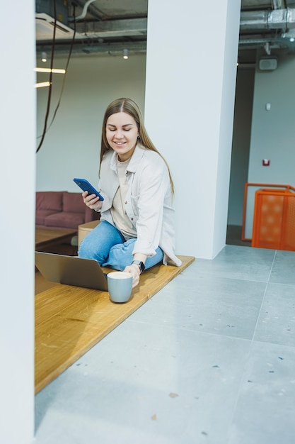 A female student works in a bright cafe with large windows online Remote work with a laptop in a cozy work cafe