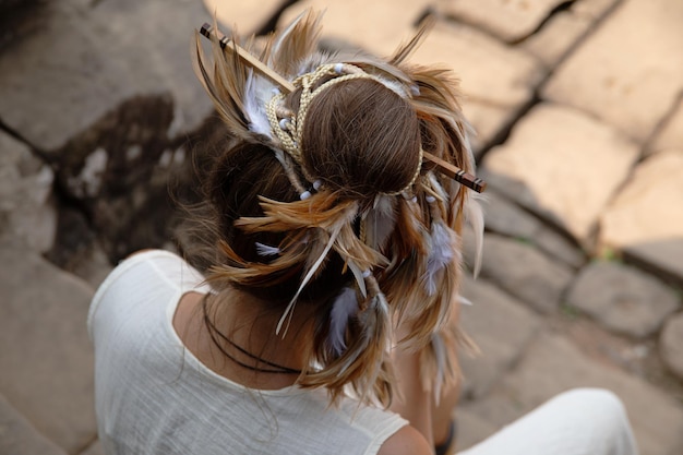 Female stylish hairdo with feathers braids and chopsticks