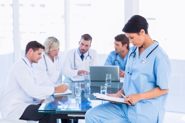 Female surgeon looking at reports with colleagues in meeting