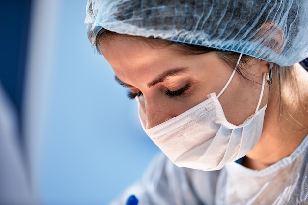 Female surgeon in operating room closeup woman doctor face during operation