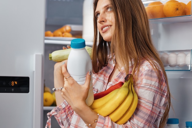 Female taking food from a fridge close up photo