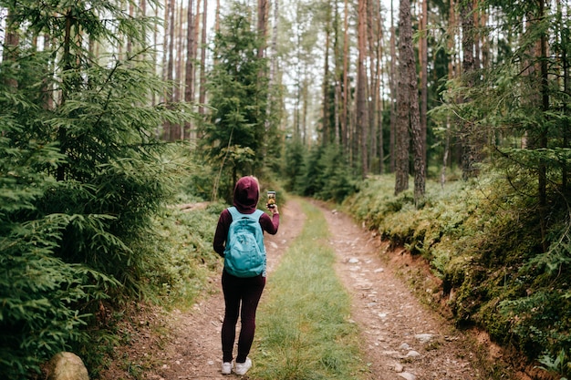 female taking photo of forest landscape with smartphone in her hand