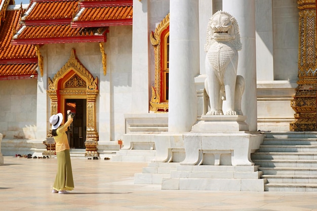 Female Taking Pictures of Guardian Lion at Wat Benchamabophit Marble Temple in Bangkok Thailand