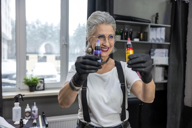 Female tattoo master holding bottles with tattoo ink