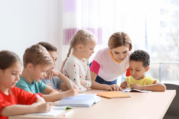 Female teacher helping children with homework in classroom at school