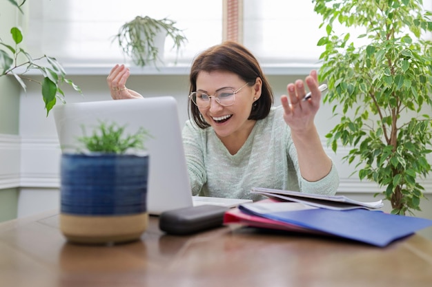 Female teacher teaching online sitting at home at table with laptop