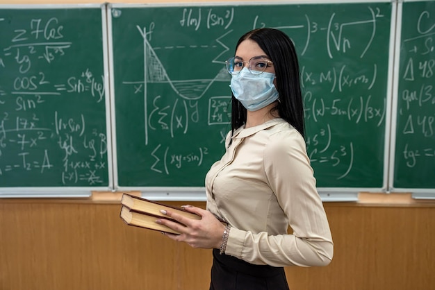 Female teacher with mask learn math lesson at school during coronavirus pandemic