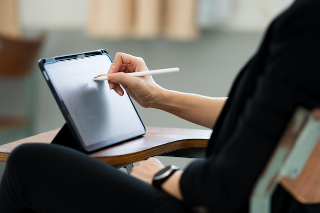 A female teacher with a tablet sits in an empty classroom at the university. while waiting to teach the students at the class