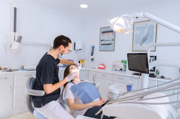 Female teeth being checked by male dentist in clinic